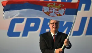 (FILES) Serbia's President Aleksandar Vucic waves a Serbian flag during a rally in Belgrade on June 27, 2026. Serbia?s President Aleksandar Vucic resigned on Sunday so he can run for prime minister in an October snap election called after nearly two years of student-led protests. "I am resigning as president," Vucic said from the presidential palace, where supporters chanted his name. "Tomorrow morning I will hand over my duties to the parliament speaker," he added. (Photo by OLIVER BUNIC/AFP)