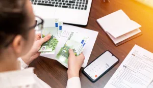 Woman working with finances counting money on the table. Smertphone, notepadbanka kredit novac račun bankrot financije ilustracija freepik