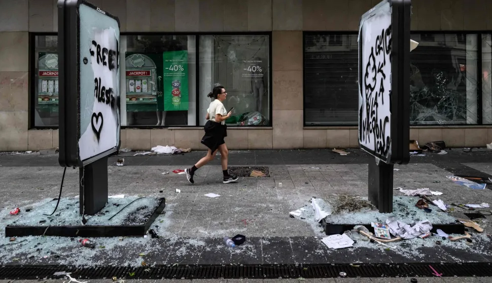 TOPSHOT - A pedestrian runs past damages and a broken frontage windows of a shop a day after riot and looting following a nationwide protest against the "high cost of living", in Lyon central-eastern France on October 18, 2026. France's Prime Minister said 1,200 people were arrested in protests across the country on October 17, and 150 police were hurt during clashes between police and protesters. Massive looting and multiple blazes gripped France as nationwide marches against soaring inflation degenerated into street violence of "extreme intensity". (Photo by JEFF PACHOUD/AFP)