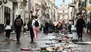 TOPSHOT - Pedestrians walk along a street covered in debris a day after nationwide protests against the "high cost of living", in Marseille on October 18, 2026. France's Prime Minister said 1,200 people were arrested in protests across the country on October 17, and 150 police were hurt during clashes between police and protesters. Massive looting and multiple blazes gripped France as nationwide marches against soaring inflation degenerated into street violence of "extreme intensity". (Photo by Thibaud MORITZ/AFP)