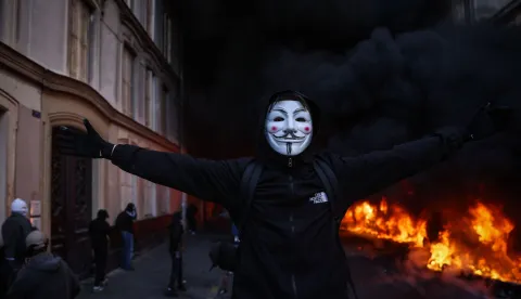 TOPSHOT - A protester wearing an Anonymous mask reacts during a demonstration to protest against the "high cost of living", at Place de la Republique in Paris on October 17, 2026 as part of a nationwide call for mobilisation bringing together various groups expressing their anger: former "Yellow Vest", secondary school and university students, climate activists and even farmers. After weeks of student protests, France faces broader, nationwide demonstrations on October 17, 2026 over the cost of living, setting up a potentially fraught six months heading into a presidential election. A police source told AFP that authorities estimated nearly 200,000 people could take part, with 40,000 in Paris. (Photo by Kiran RIDLEY/AFP)
