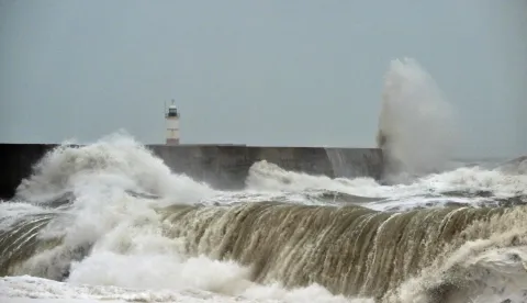 Waves crash over onto the beach near Newhaven Lighthouse and the breakwater in Newhaven, southern England on October 23, 2026, as Storm Austen brought strong winds and heavy rain across much of southern England. Storm Auste (Photo by GLYN KIRK/AFP)