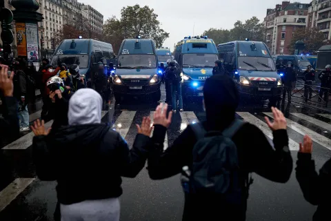 TOPSHOT - Protesters raise their hands facing French Gendarmerie vehicles during a demonstration in favor of purchasing power, the protection of public services, and fiscal and social justice, in Paris on October 24, 2026 as part of a nationwide call for mobilisation bringing together former members of the Yellow Vest movement, labor unions, high school and university students. Protests by high school students over learning conditions sparked a movement that has since spread nationwide, fuelled by broader anger over the rising cost of living. About 70,000 security personnel will be deployed on October 24, 2026, Interior Minister said at a news conference, warning that calls for violence and looting were circulating on social media. (Photo by Sameer AL-DOUMY/AFP)