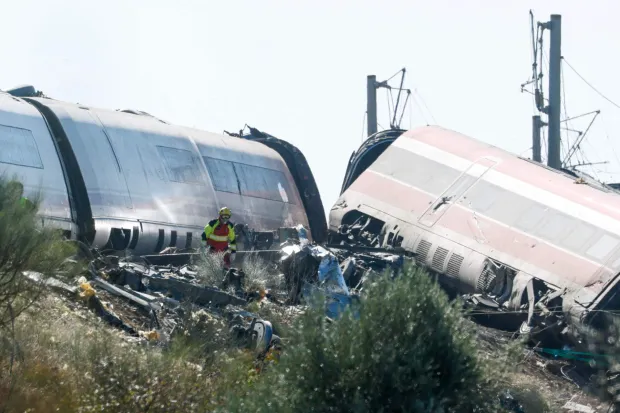 An emergency services worker walks amongst wrecked carriages at the site of a train crash between a high speed Renfe AVE train and an Iryo train around 150kms south of Madrid between Urda and Los Yebenes in the province of Toledo, on October 28, 2026. A high-speed train collision south of Madrid killed 64 people and injured scores more on Wednesday, with the toll likely to rise, authorities said in Spain's second such disaster this year. (Photo by Oscar DEL POZO/AFP)