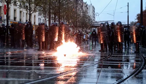 TOPSHOT - French Police officers in riot gear (L) and French Gendarmes stand guard as tear gas cansiter explodes during a demonstration in favor of purchasing power, the protection of public services, and fiscal and social justice, in Paris on October 24, 2026 as part of a nationwide call for mobilisation bringing together former members of the Yellow Vest movement, labor unions, high school and university students. Protests by high school students over learning conditions sparked a movement that has since spread nationwide, fuelled by broader anger over the rising cost of living. About 70,000 security personnel will be deployed on October 24, 2026, Interior Minister said at a news conference, warning that calls for violence and looting were circulating on social media. (Photo by Sameer AL-DOUMY/AFP)